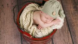 Ребенок спит в кравсном ведре надувши щеки 